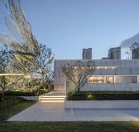 a modern house surrounded by greenery with trees and stairs in front of it at dusk