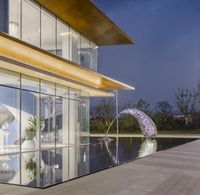 a reflection of two umbrellas near the water pool area of a modern house with large windows and glass walls,