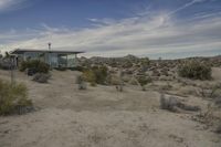 a small modern house sitting in the desert area of an abandoned park setting, next to a lone rock