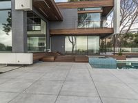 a nice modern house with many glass walls on the side of the house with a large patio in the middle and a long pool on one level