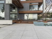 a nice modern house with many glass walls on the side of the house with a large patio in the middle and a long pool on one level