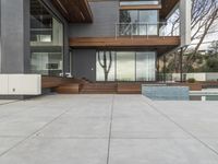 a nice modern house with many glass walls on the side of the house with a large patio in the middle and a long pool on one level