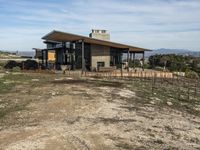 a big house sitting on top of a hill near dirt and grass in the country