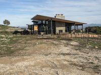 a big house sitting on top of a hill near dirt and grass in the country