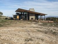 a big house sitting on top of a hill near dirt and grass in the country