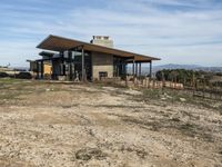 a big house sitting on top of a hill near dirt and grass in the country