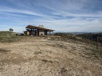 a big house sitting on top of a hill near dirt and grass in the country