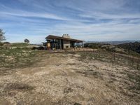 a big house sitting on top of a hill near dirt and grass in the country