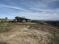 a big house sitting on top of a hill near dirt and grass in the country