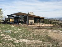 a big house sitting on top of a hill near dirt and grass in the country