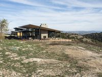 a big house sitting on top of a hill near dirt and grass in the country