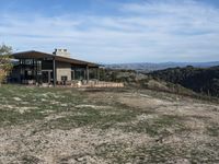 a big house sitting on top of a hill near dirt and grass in the country