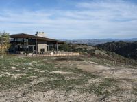 a big house sitting on top of a hill near dirt and grass in the country