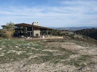 a big house sitting on top of a hill near dirt and grass in the country