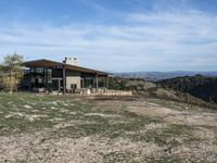 a big house sitting on top of a hill near dirt and grass in the country