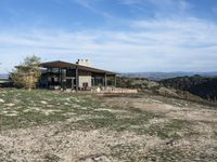 a big house sitting on top of a hill near dirt and grass in the country