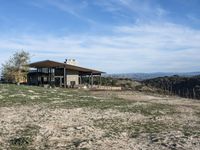 a big house sitting on top of a hill near dirt and grass in the country