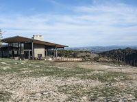 a big house sitting on top of a hill near dirt and grass in the country