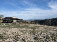 a big house sitting on top of a hill near dirt and grass in the country