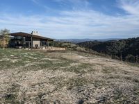 a big house sitting on top of a hill near dirt and grass in the country