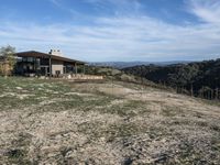 a big house sitting on top of a hill near dirt and grass in the country