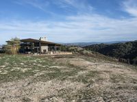 a big house sitting on top of a hill near dirt and grass in the country