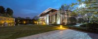 this modern house is lit up at night in the evening time with outdoor lighting and greenery