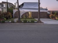 a house that is next to two palm trees with a white canopy attached to it