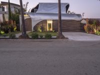 a house that is next to two palm trees with a white canopy attached to it