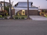 a house that is next to two palm trees with a white canopy attached to it