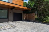 a modern house features paver stone with a wood ceiling over entrance and fenced in area