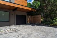 a modern house features paver stone with a wood ceiling over entrance and fenced in area