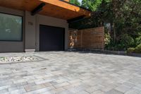 a modern house features paver stone with a wood ceiling over entrance and fenced in area