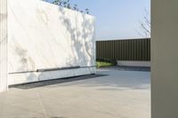 the outside courtyard of an all white modern house in palm springs florida with concrete bench and trees