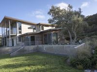 the house with large grass lawn is surrounded by plants and landscaping in a modern house