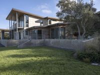 the house with large grass lawn is surrounded by plants and landscaping in a modern house