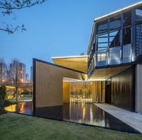 a modern house that features an expansive courtyard, covered by wooden panels and illuminated in lights