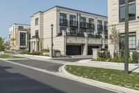 a row of modern housing buildings next to a sidewalk near some bushes and trees on a sunny day