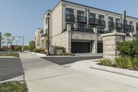 a row of modern housing buildings next to a sidewalk near some bushes and trees on a sunny day