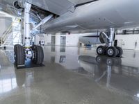 an airplane is parked in a room with some big tires on the floor in front of the plane