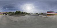 a skateboarder doing a trick at a skate park with a sky background and sun in the background