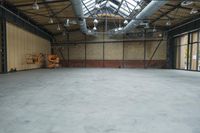 an empty industrial space with exposed brick walls and concrete floors is shown in this photograph