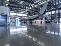 an airplane sits in an airplane hangar and is reflected in the floor of the building