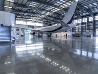 an airplane sits in an airplane hangar and is reflected in the floor of the building