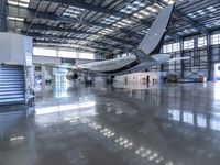 an airplane sits in an airplane hangar and is reflected in the floor of the building