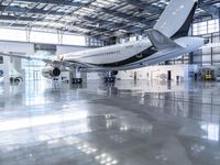 an airplane sits in an airplane hangar and is reflected in the floor of the building