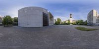 the panoramic image shows a building on an island near trees and a clock tower