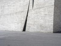 an empty parking lot near a white wall with a concrete pipe sticking out of it