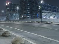 the empty city road is empty by the tall building in the background at night with light streaking on the buildings