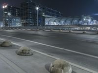 the empty city road is empty by the tall building in the background at night with light streaking on the buildings